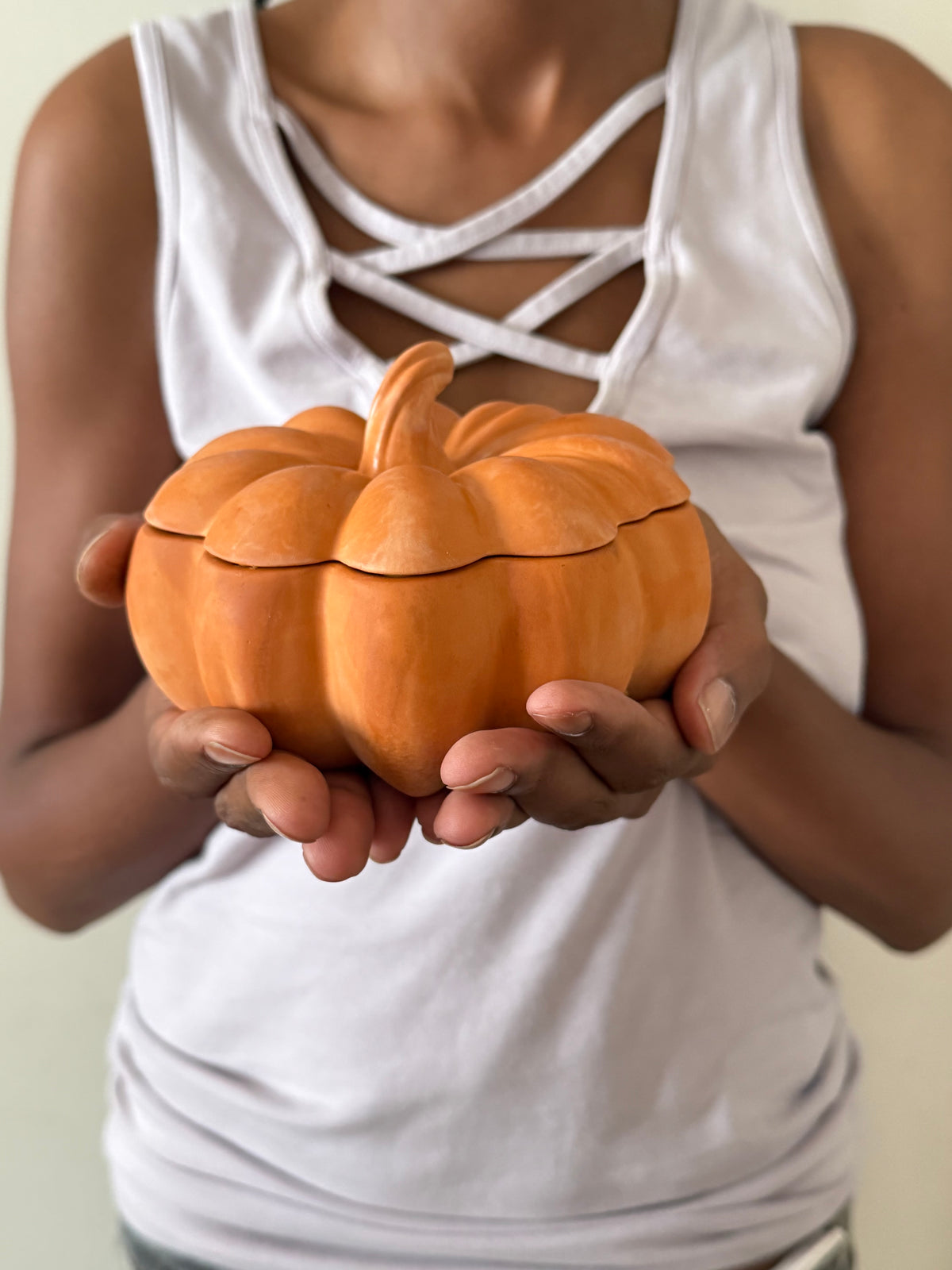 Hands holding a handmade concrete pumpkin candle to show its size